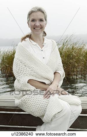 Older woman sitting on wooden dock View Large Photo Image Stock Image - Older woman sitting on wooden dock. Fotosearch