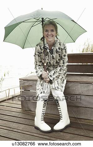 Older woman sitting under umbrella View Large Photo Image Stock Photograph - Older woman sitting under umbrella. Fotosearch