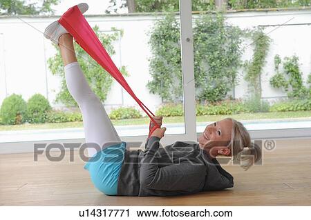 Stock Image - Older woman using exercise band at home. Fotosearch