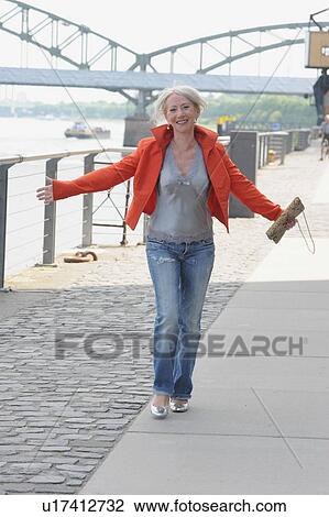 Older woman walking along riverfront View Large Photo Image Stock Image - Older woman walking along riverfront. Fotosearch