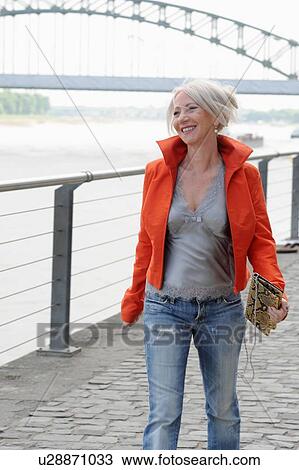 Older woman walking along riverfront View Large Photo Image Stock Image - Older woman walking along riverfront. Fotosearch