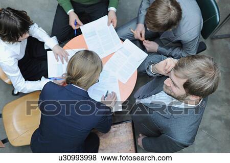 Stock Photo - Overhead view of business people at desk. Fotosearch