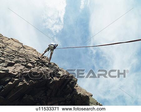 Rock climber rappelling down rock face View Large Photo Image Stock Image - Rock climber rappelling down rock face. Fotosearch
