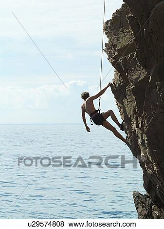 Rock climber rappelling down rock face View Large Photo Image Stock Photo - Rock climber rappelling down rock face. Fotosearch