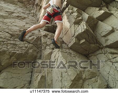 Stock Photography - Rock climber scaling steep rock face. Fotosearch