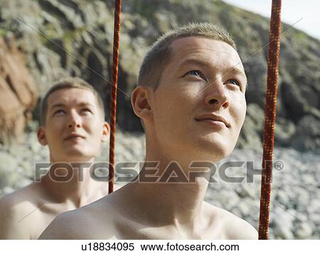 Stock Photography - Rock climbers holding cord taut on beach. Fotosearch