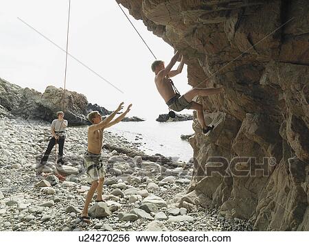 Stock Photograph - Rock climbers rappelling down rock face. Fotosearch
