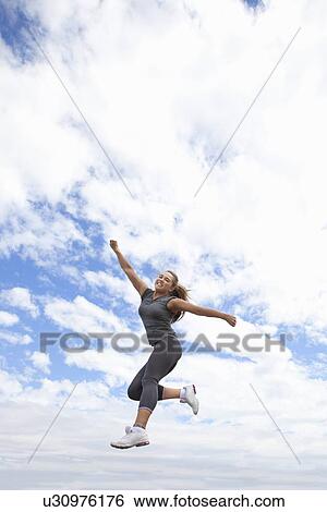 Stock Photograph - Runner jumping for joy outdoors. Fotosearch