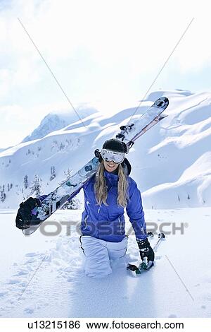 Stock Photograph - Skier carrying skis in snow. Fotosearch