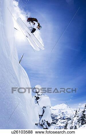 Stock Photo - Skier jumping on snowy slope. Fotosearch