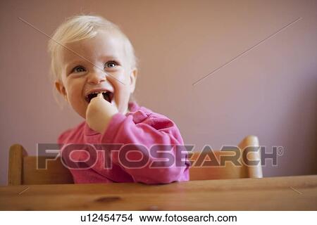Smiling baby girl sitting at table View Large Photo Image Picture - Smiling baby girl sitting at table. Fotosearch