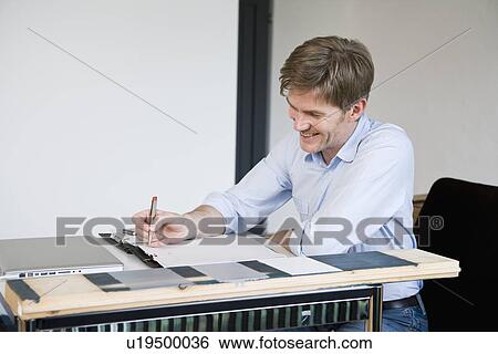 Stock Photograph - Smiling businessman working at desk. Fotosearch