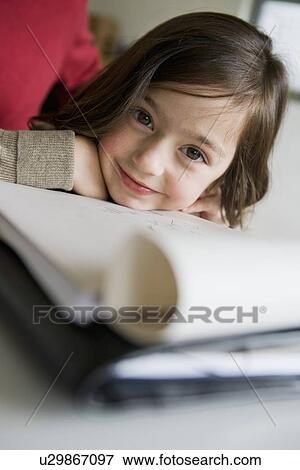 Smiling girl doing her homework at desk View Large Photo Image Stock Photo - Smiling girl doing her homework at desk. Fotosearch