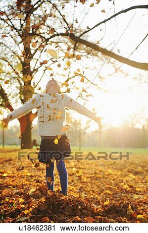 Smiling girl playing in autumn leaves View Large Photo Image Stock Image - Smiling girl playing in autumn leaves. Fotosearch