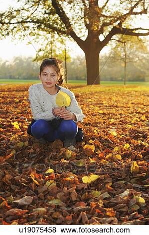 Smiling girl playing in autumn leaves View Large Photo Image Stock Photo - Smiling girl playing in autumn leaves. Fotosearch