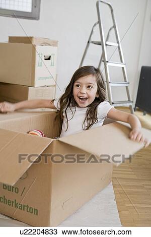Stock Image - Smiling girl playing in cardboard box. Fotosearch