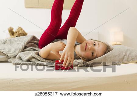 Smiling girl playing with toy bus in bed View Large Photo Image Stock Photo - Smiling girl playing with toy bus in bed. Fotosearch