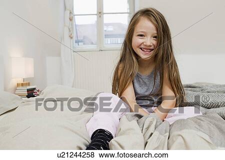 Smiling girl sitting on bed View Large Photo Image Stock Photo - Smiling girl sitting on bed. Fotosearch