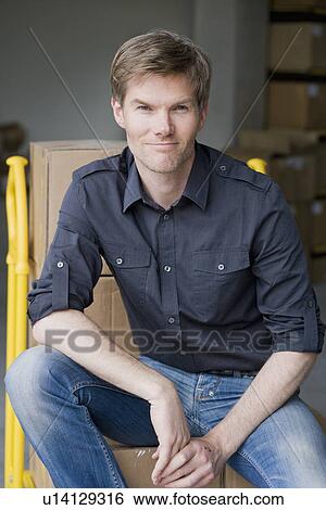 Smiling man sitting on boxes on dolly View Large Photo Image Stock Photograph - Smiling man sitting on boxes on dolly. Fotosearch