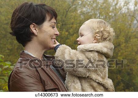 Smiling mother holding toddler outdoors View Large Photo Image Stock Image - Smiling mother holding toddler outdoors. Fotosearch
