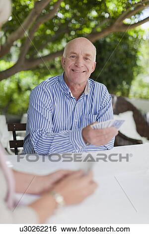 Stock Photograph - Smiling older couple playing cards. Fotosearch