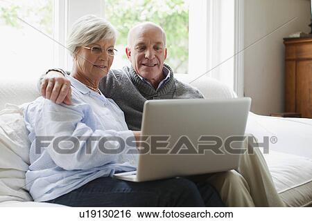 Smiling older couple using laptop View Large Photo Image Stock Photograph - Smiling older couple using laptop. Fotosearch