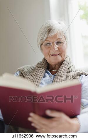 Stock Photograph - Smiling older woman reading book. Fotosearch