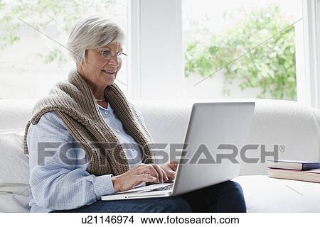 Smiling older woman using laptop View Large Photo Image Picture - Smiling older woman using laptop. Fotosearch