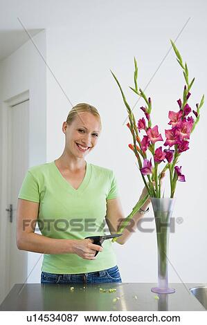 Stock Photo - Smiling woman arranging flowers in vase. Fotosearch