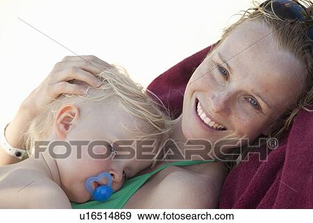 Smiling woman cuddling baby on beach View Large Photo Image Stock Photo - Smiling woman cuddling baby on beach. Fotosearch