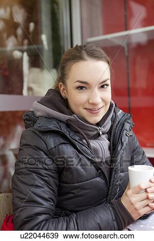 Stock Photo - Smiling woman having coffee outdoors. Fotosearch