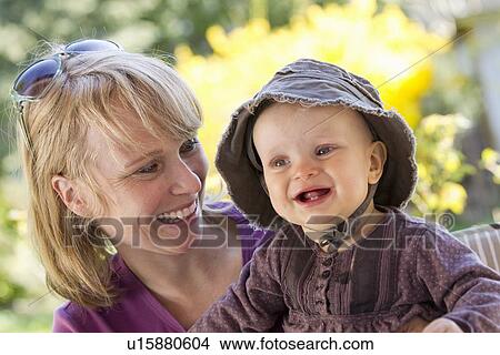 Smiling woman holding baby girl View Large Photo Image Picture - Smiling woman holding baby girl. Fotosearch