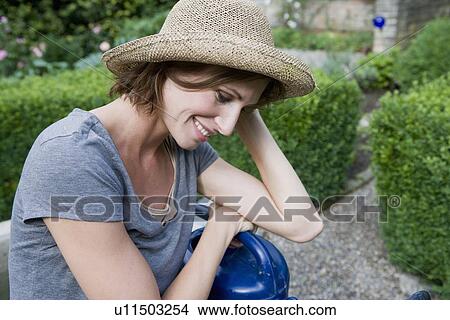 Smiling woman holding watering can View Large Photo Image Picture - Smiling woman holding watering can. Fotosearch