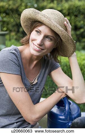 Stock Image - Smiling woman holding watering can. Fotosearch