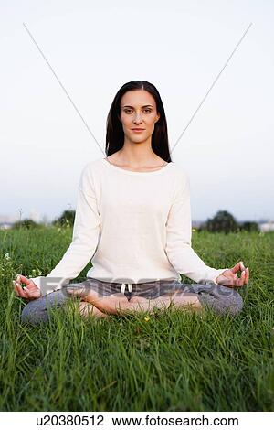 Stock Image - Smiling woman meditating in park. Fotosearch