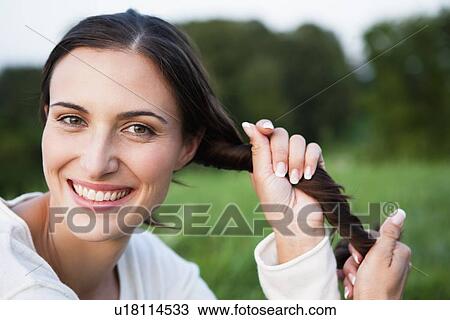 Stock Image - Smiling woman playing with her hair. Fotosearch