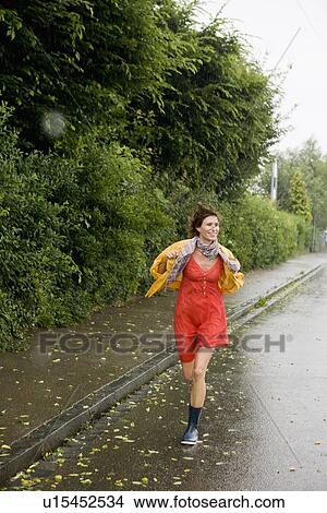 Picture - Smiling woman running in rain. Fotosearch