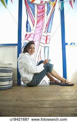 Stock Photo - Smiling woman sitting by Union Jack flag. Fotosearch