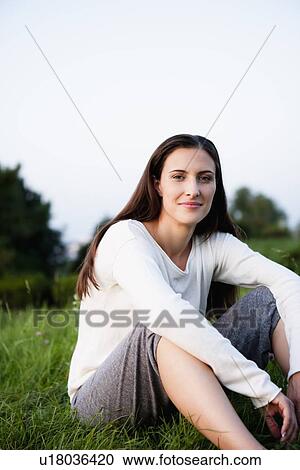 Stock Image - Smiling woman sitting in park. Fotosearch