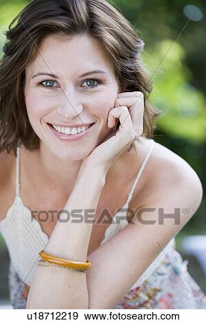 Stock Photo - Smiling woman sitting outdoors. Fotosearch