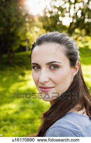 Stock Image - Smiling woman standing in park. Fotosearch