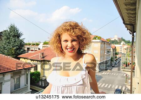 Smiling woman standing on balcony View Large Photo Image Stock Photography - Smiling woman standing on balcony. Fotosearch