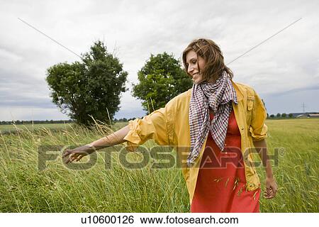 Smiling woman walking in tall grass View Large Photo Image Stock Photograph - Smiling woman walking in tall grass. Fotosearch
