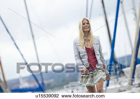 Stock Image - Smiling woman walking on pier. Fotosearch