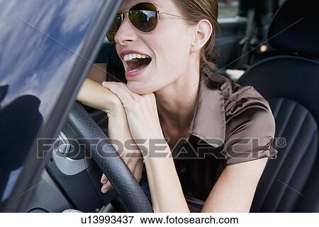 Smiling woman wearing sunglasses in car View Large Photo Image Stock Photo - Smiling woman wearing sunglasses in car. Fotosearch