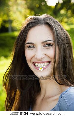 Picture - Smiling woman with flower in park. Fotosearch