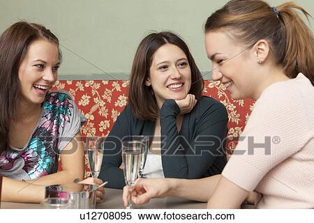 Stock Photography - Smiling women having champagne in cafe. Fotosearch