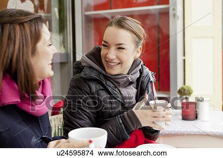 Picture - Smiling women having coffee outdoors. Fotosearch