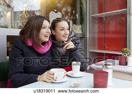 Stock Image - Smiling women having coffee outdoors. Fotosearch
