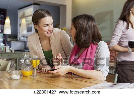 Stock Photo - Smiling women talking in cafe. Fotosearch